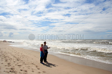Daenemark  Paar steht am Strand und schaut auf das Meer