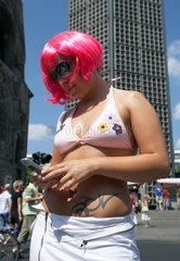 Berlin  eine junge Frau in schrillem Outfit mit einem Mobiltelefon