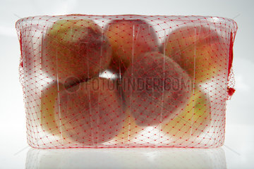 Spanische Pfirsiche in einer Plastikschale umhuellt von einem roten Netz
