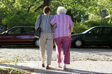 Berlin  eine Frau hilft einer Rentnerin ueber die Strasse