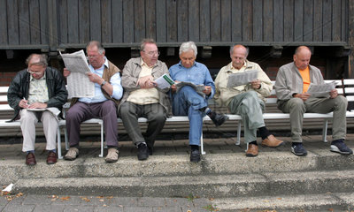 Dresden  aeltere Maenner sitzen auf Parkbaenken und lesen Zeitungen