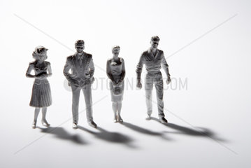 Vier Miniaturfiguren mit Schlagschatten vor weissem Hintergrund