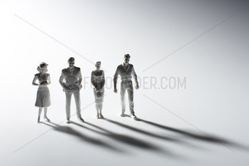 Vier Miniaturfiguren mit Schlagschatten vor weissem Hintergrund