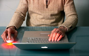 Ein Mann sitzt an einem Glastisch mit einem Laptop