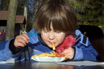 Ein Kind isst Pommes frites