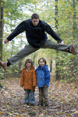 Ein Mann springt ueber zwei Kinder