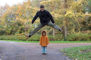 Ein Mann springt ueber ein Kind im Park