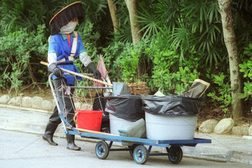 Eine Frau beim Reinigen der Strassen in Kowloon