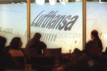 Reisende warten vor einer Lufthansa Maschine