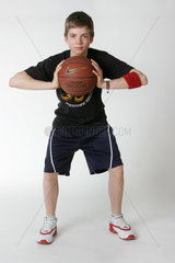 Ein Junge posiert mit einem Basketball