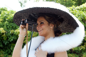 Royal Ascot  schoene Frau mit Hut und Fernglas auf der Galopprennbahn