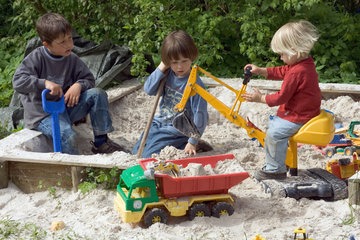 Drei Kinder spielen im Sandkasten
