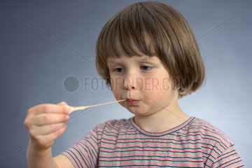 Ein Kind zieht einen Kaugummi aus dem Mund