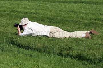 Ein Fotograf fotografiert im Gras liegend