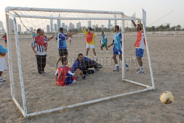 Dubai  Maenner beim Fussballspielen. Im Hintergrund die Skyline