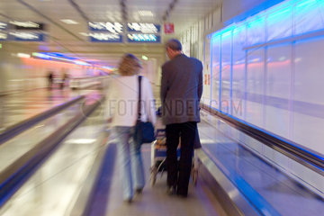 Muenchen  Reisende in einem Gang des Muenchener Flughafen auf einer Rolltreppe