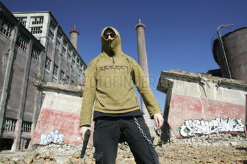 Ein Jugendlicher mit einer Waffe vor einer Fabrikruine