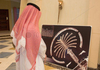 Dubai  Ein Araber besichtigt ein Bild der Palm Jumeirah