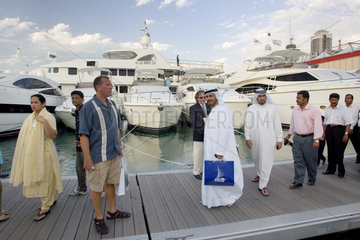 Dubai  eine Gruppe arabischer Maenner vor Luxusyachten im Yachthafen