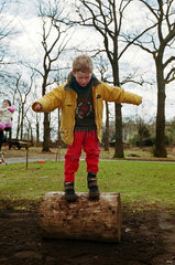 Junge balanciert auf einem Baumstumpf im Garten  Norddeutschland