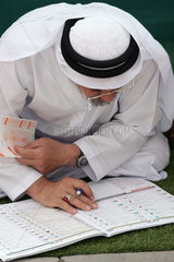 Dubai  ein Mann beim Studieren des Rennprogramms auf der Rennbahn von Nad Al Sheba