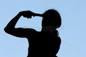 Symbolfoto  ein Mensch haelt sich eine Pistole an die Schlaefe