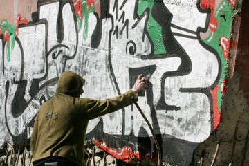Brandenburg  ein Jugendlicher sprueht ein Graffiti an eine Wand