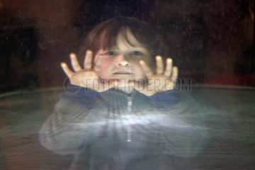 Ein Kind sieht durch eine Glasscheibe