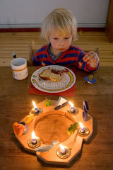 Berlin  ein kleiner Junge sieht erstaunt auf die Kerzen an seinem Geburtstagskranz