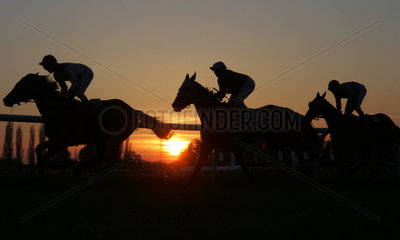Jockeys mit ihren Pferden im Sonnenuntergang
