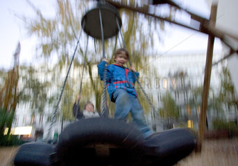 Berlin  Kinder beim Schaukeln auf dem Spielplatz