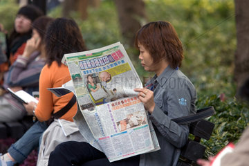Hong Kong  Frau liest in einer Zeitung