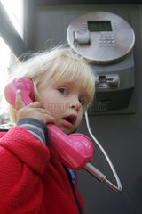 Berlin  ein Kleinkind beim Telefonieren in einer Telefonzelle