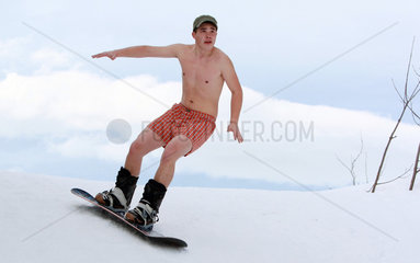 Krippenbrunn  Oesterreich  junger Mann in Boxershorts faehrt Snowboard