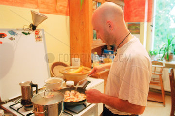 Berlin  ein Mann beim Kochen in der Kueche