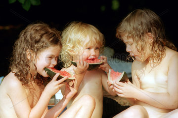 Drei kleine Kinder essen Melone