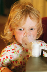 Ein Kind inhaliert mit Hilfe eines Geraetes