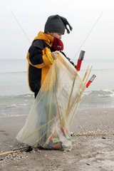 Zingst  ein Kind sammelt abgebrannte Silvesterraketen am Strand