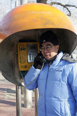 Peking  ein Mann telefoniert an einem oeffentlichen Fernsprecher