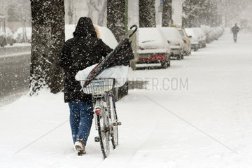 Berlin  eine Frau schiebt ihr Fahrrad auf verschneiter Strasse
