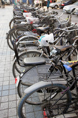 Peking  Abgestellte Fahrraeder auf einer Strasse
