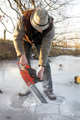 Prangendorf  Mann saegt ein Loch in einen zugefrorenen See