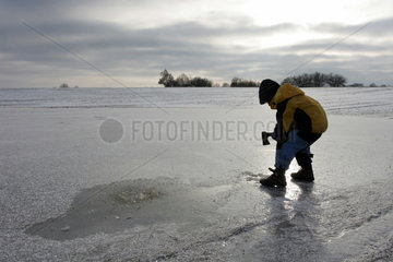 Prangendorf  Kind schlaegt ein Loch in einen zugefrorenen See