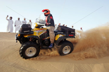 Dubai  eine Gruppe arabischer Maenner beobachtet einen Quadfahrer in der Wueste