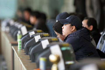 Seoul  Rennbahnbesucher sitzen vor Monitoren in der Wetthalle