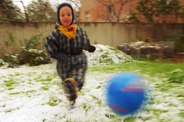ein Junge schiesst einen blauen Fussball