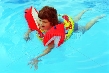 Ein Kind lernt schwimmen in einem Swimmingpool