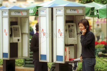 Eine junge Frau telefoniert an einer Telefonzelle der Telefongesellschaft CTM
