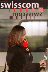 Eine Frau steht in einer Telefonzelle der Schweizer Telefongesellschaft Swisscom