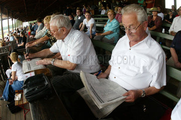 Zuschauer beim Lesen der Fachzeitung auf der Galopprennbahn
